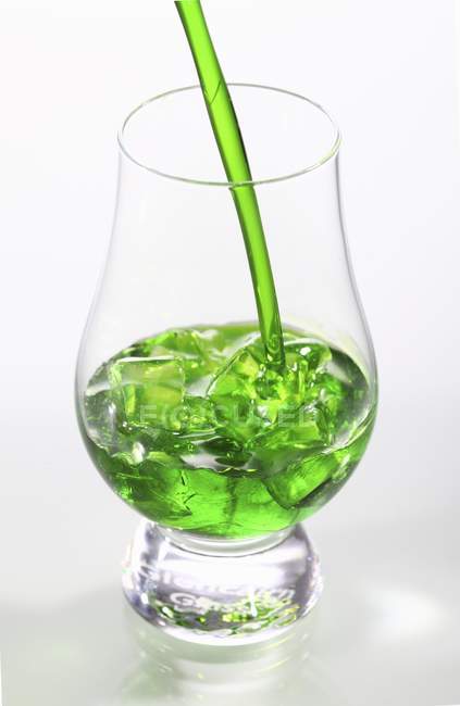 Closeup view of green liqueur with ice and straw in glass — Stock Photo