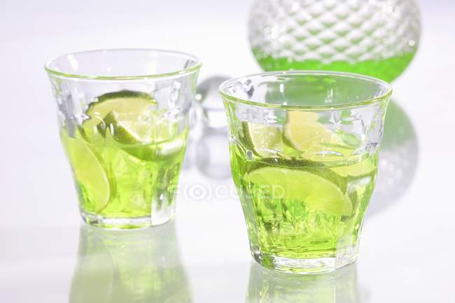 Lime liqueur in glasses over white surface — Stock Photo