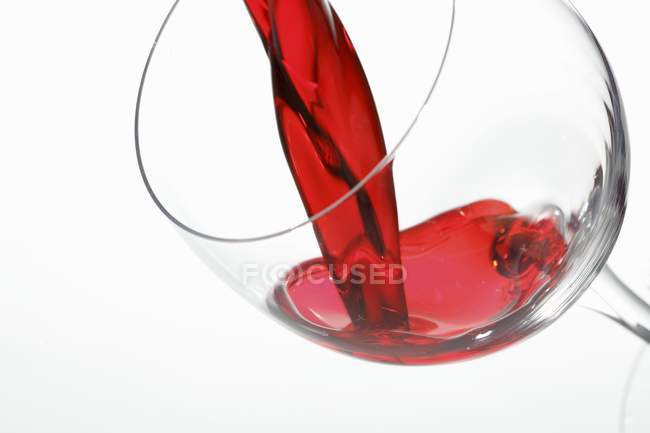Vinho tinto sendo derramado em um copo — Fotografia de Stock