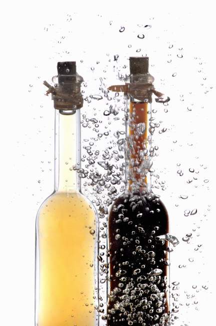 Vinagre e garrafas de óleo na água com bolhas de ar — Fotografia de Stock