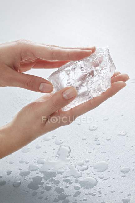 Vista de cerca de las manos sosteniendo un pedazo de hielo - foto de stock