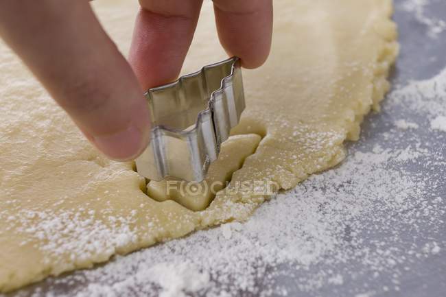 Closeup view of hand cutting out Christmas tree-shaped cookie — Stock Photo