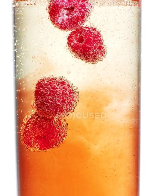 Frambuesas maduras en champán frío - foto de stock