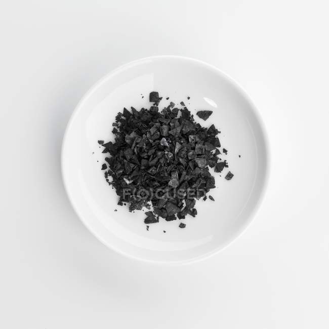 Plate of black sea salt grains — Stock Photo