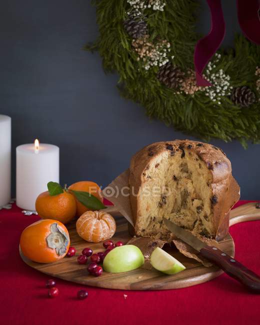 Closeup view of Italian panettone on cutting board with fruit — Stock Photo