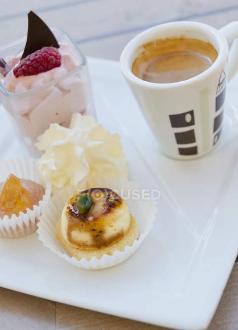 Vista close-up de café e uma seleção de sobremesas em uma placa de porcelana — Fotografia de Stock