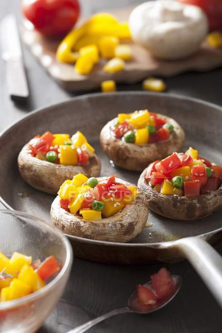 Mushrooms stuffed with tomatoes, yellow peppers and peas — Stock Photo