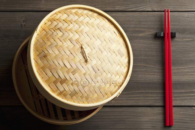 Nahaufnahme eines Bambusdampfers und roter Essstäbchen — Stockfoto