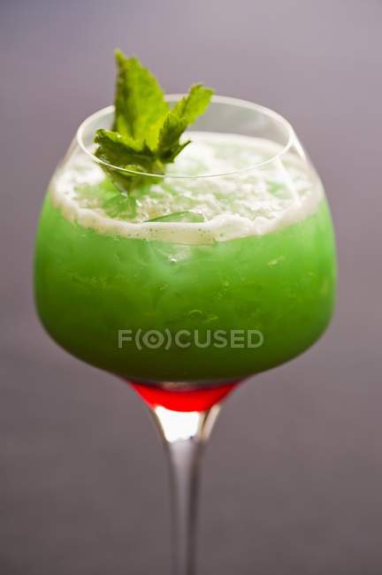 Closeup view of Tropical Sunrise cocktail with ice cubes and leaves — Stock Photo