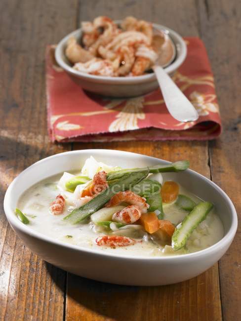 Cray fish, potato, carrot and asparagus stew in dish over wooden surface — Stock Photo