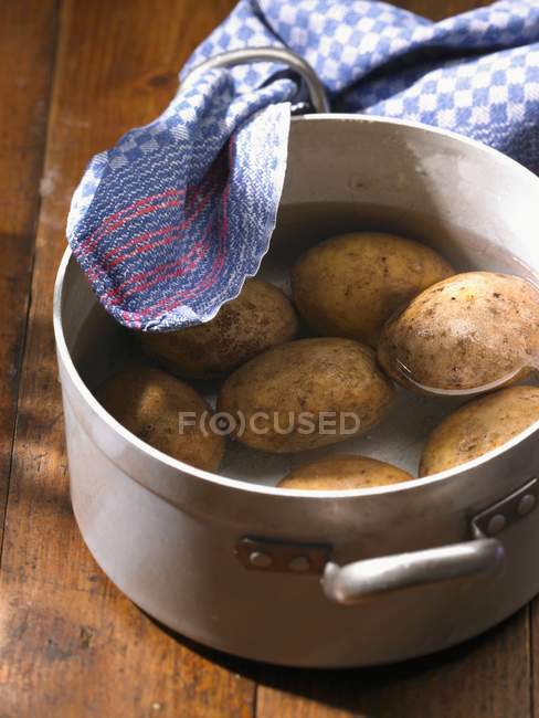Patatas en olla de agua - foto de stock