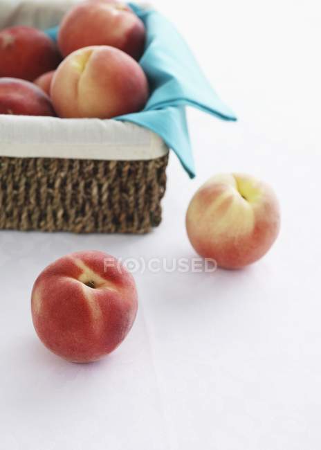 Fresh peaches in rustic basket — Stock Photo