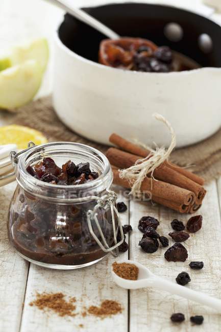Closeup view of homemade mince meat with cinnamon, spices and dried fruit in a pan and in a jar — Stock Photo