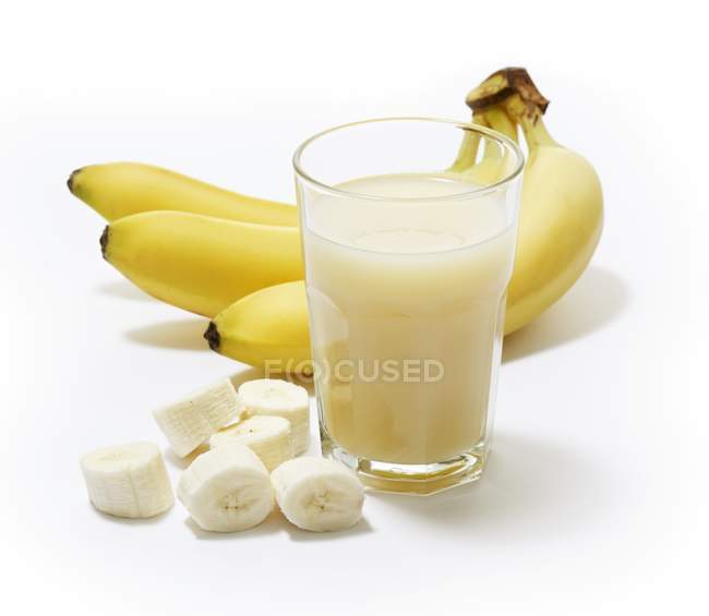 Vaso de jugo de plátano con plátanos - foto de stock