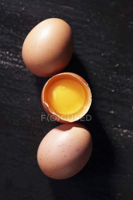 Brown whole and cracked eggs — Stock Photo