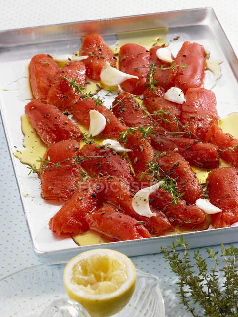 Tomatoes on a baking tray with thyme, garlic and olive oil on baking tray — Stock Photo