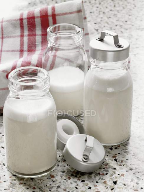 Bottles of almond milk over table with towel — Stock Photo