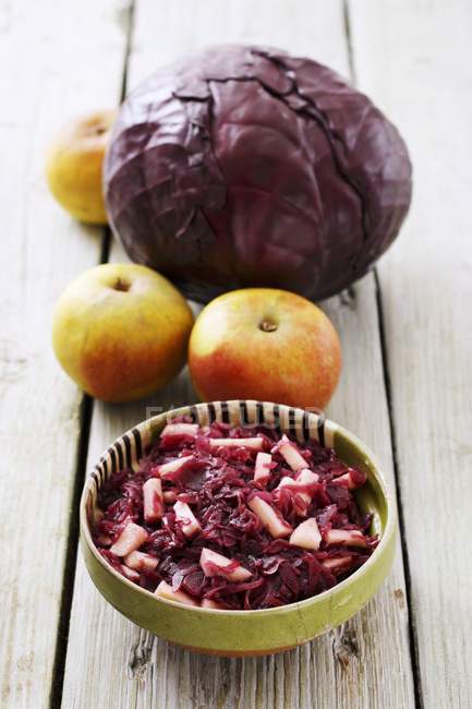Apple-red cabbage and ingredients  over wooden surface — Stock Photo