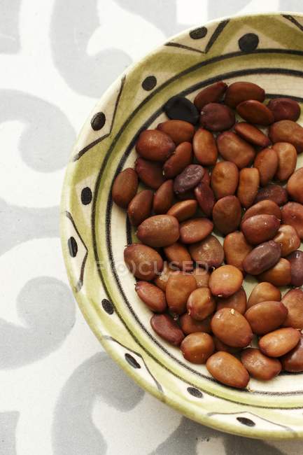 Bowl of carob bean seeds — Stock Photo