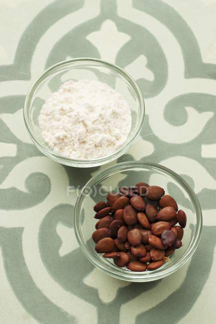 Closeup view of carob bean flour and carob bean seeds — Stock Photo