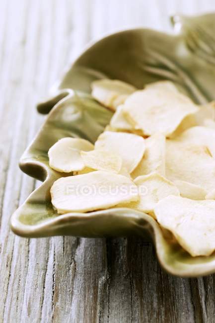 Dried garlic slices in leaf-shaped dish — Stock Photo