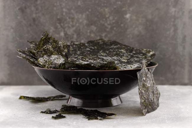 Vue rapprochée d'un bol noir de copeaux d'algues — Photo de stock