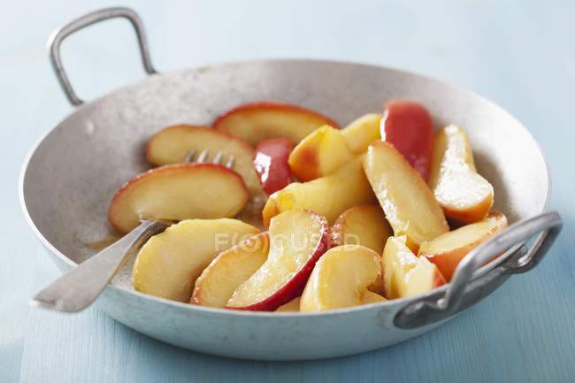 Вид крупным планом карамельных ломтиков яблок в сковороде — стоковое фото