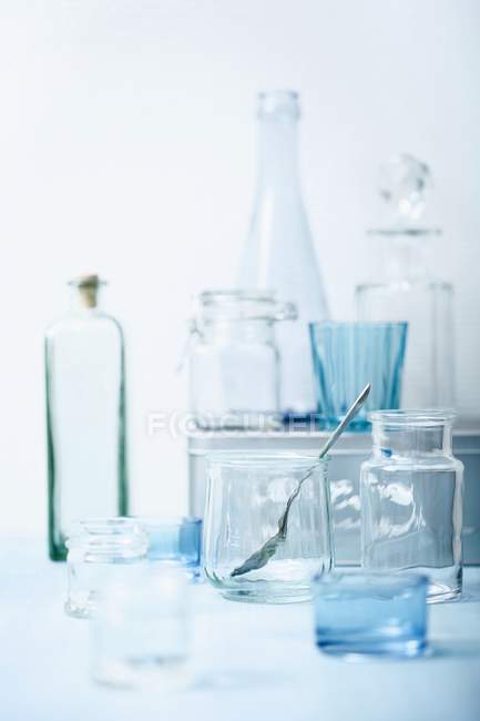 Varios vasos y botellas vacías sobre un fondo blanco - foto de stock