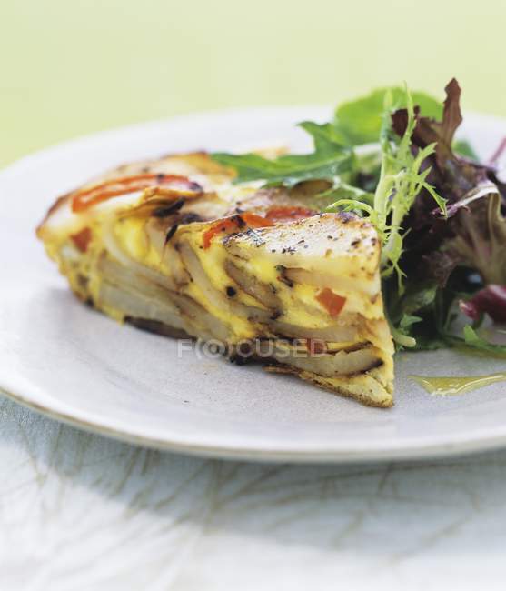 Potato and pepper frittata with a mixed leaf salad on white plate — Stock Photo