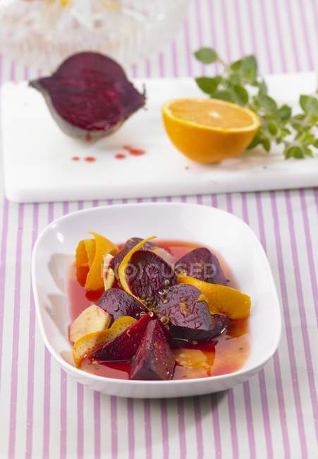 Backed beetroot with orange zest and ginger on white plate over tablecloth — Stock Photo