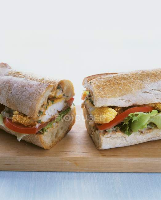 Sanduíche de baguete com peixe batido na mesa de madeira — Fotografia de Stock