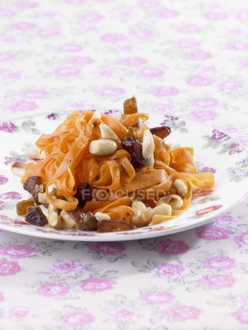 Carrot salad with dates and almonds over colored tablecloth — Stock Photo