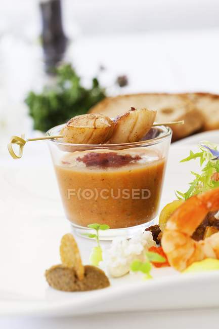 Closeup view of scallop kebab on glass of cold vegetable soup — Stock Photo