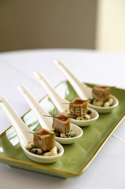 Thon frit éclair sur des haricots blancs truffés sur une assiette verte sur une surface blanche — Photo de stock
