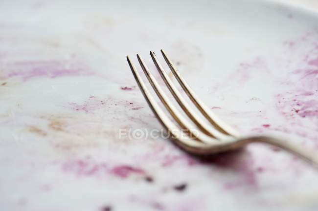 Vista close-up de um garfo em uma placa suja — Fotografia de Stock