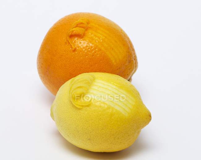 Naranja y limón con la ralladura rizada - foto de stock