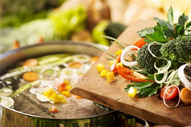 Verduras en el escritorio de madera y una olla de sopa - foto de stock