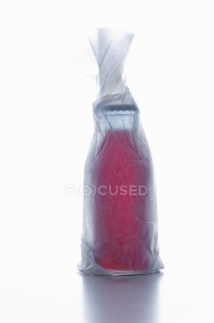 Vista de perto de uma garrafa de líquido vermelho embrulhado em papel — Fotografia de Stock