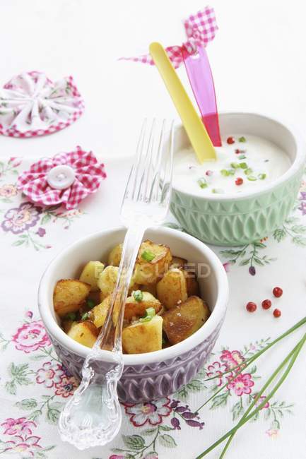 Batatas fritas com um molho de cebolinha e pimenta vermelha em tigelas sobre toalha de mesa — Fotografia de Stock