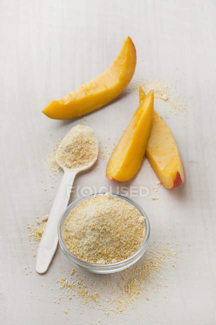 Nahaufnahme von Mango-Fruchtpulver in einer Glasschüssel und auf einem Löffel — Stockfoto