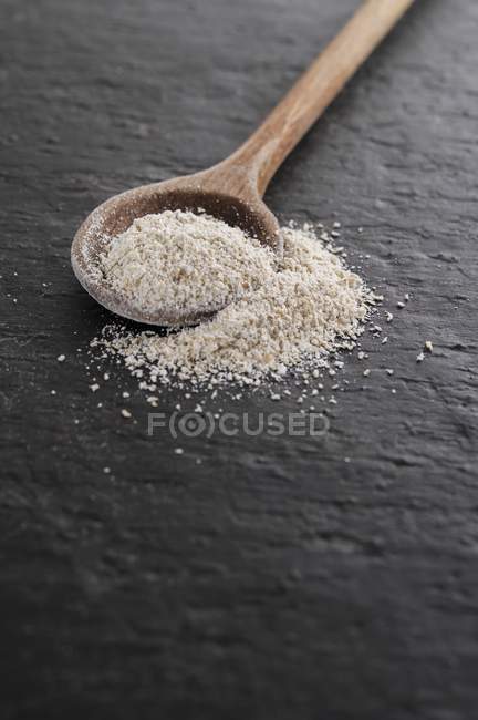 Closeup view of spelt semolina and wooden spoon — Stock Photo