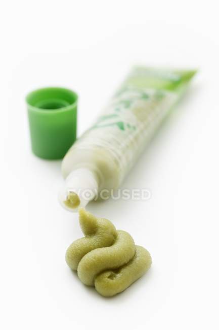 Vista close-up de um tubo de wasabi em uma superfície branca — Fotografia de Stock