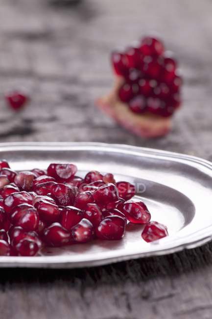 Pomegranate seeds on silver plate — Stock Photo