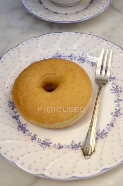 Пончик и вилка на тарелке — стоковое фото