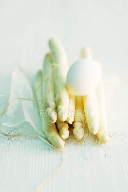 A hard-boiled egg on a bunch of white asparagus tied with twine — Stock Photo