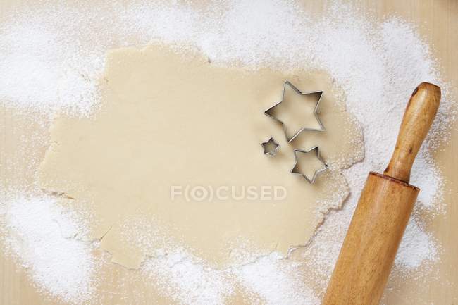 Top view of rolled out cookie dough with star-shaped cutters and rolling pin — Stock Photo