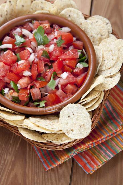 Bowl of Fresh Salsa with Tortilla Chips over wooden surface — Stock Photo
