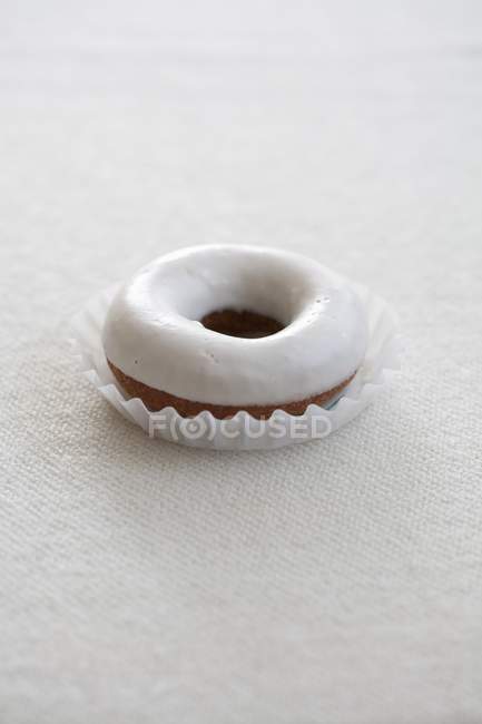 Closeup view of one glazed donut on white surface — Stock Photo