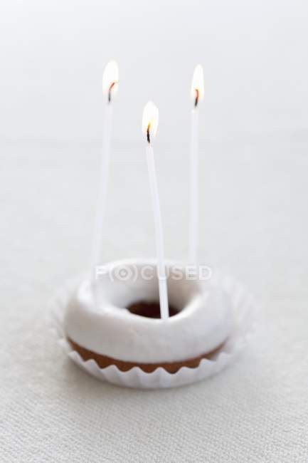 Beignet avec sucre glace et trois bougies — Photo de stock