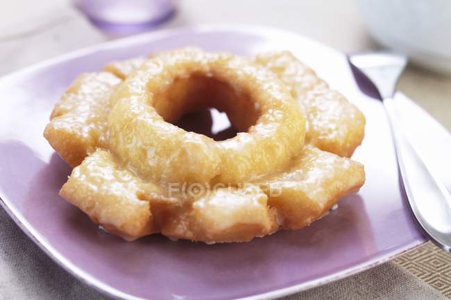 Doughnut glacé sur une assiette pourpre — Photo de stock